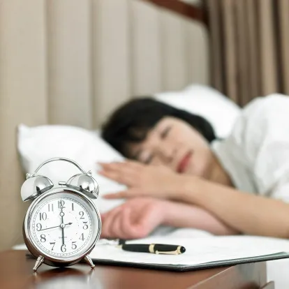 women sleeping with alarm clock in view