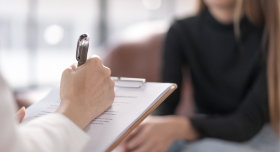 A client seated across from someone writing on a clipboard