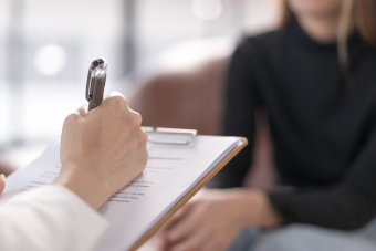 A client seated across from someone writing on a clipboard